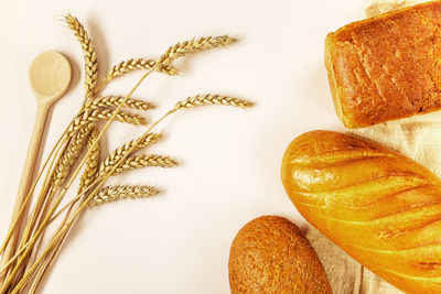 Layout of ears of ripe wheat and three different loaves of bread on light background. background