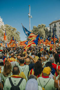 Group of people in traditional flags against sky in city