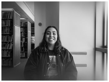 Portrait of smiling young woman standing in corridor