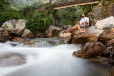 Rear view of man standing against waterfall