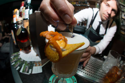 Young bartender making cocktail in counter