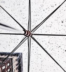 Low angle view of wet transparent umbrella against sky during monsoon