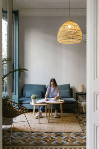 Young woman sitting on table at home