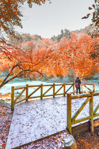 Man standing by railing during autumn