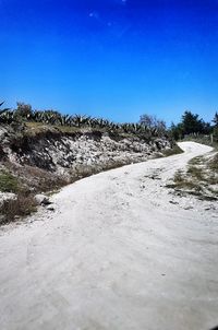 Surface level of road against clear blue sky