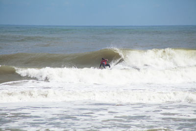 People surfing on sea against clear sky