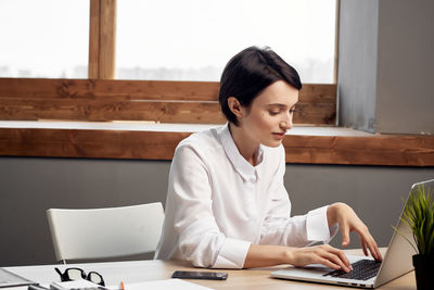 Woman using laptop while sitting at office