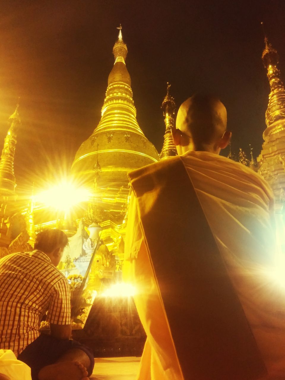 low angle view, sun, illuminated, religion, lens flare, place of worship, sunbeam, spirituality, architecture, built structure, building exterior, sky, sunlight, temple - building, sunset, outdoors, night, gold colored, glowing