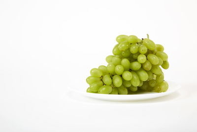 Close-up of grapes in plate against white background
