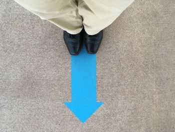 Low section of man standing on blue arrow symbol