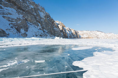 Frozen lake and mountains against sky