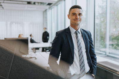 Portrait of confident young businessman standing at corporate office