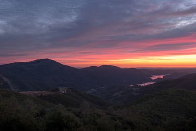 Scenic view of mountains against dramatic sky during sunset