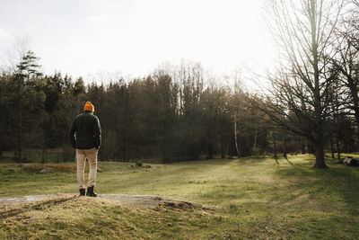 Rear view of man standing on field against sky