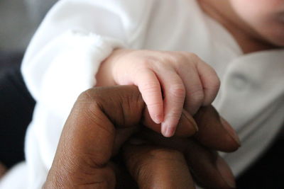 Midsection of baby holding finger while sleeping