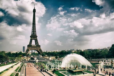 View of fountain in city against cloudy sky