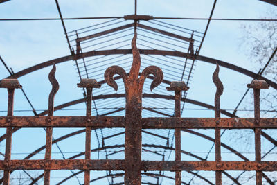 Low angle view of rusty metal fence against sky