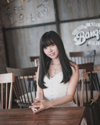 Portrait of young woman sitting on table