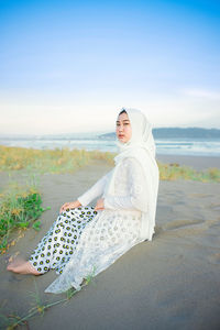 Portrait of young woman standing against sky