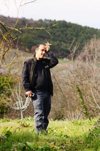 Man holding cigarette looking away while standing against dry plants