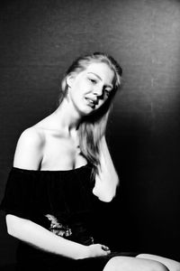 Portrait of female model sitting on seat against wall