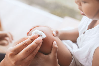 Cropped hand of mother applying medicine on daughter wounded knee