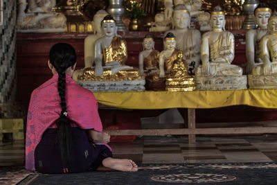 Rear view of woman sitting in temple against building