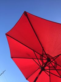 Low angle view of red umbrella against clear blue sky