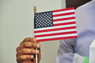 Close-up of hand holding american flag against wall