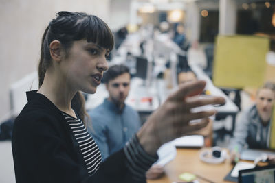 Computer programmer explaining adhesive note to colleagues in office