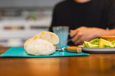 Freshly sliced baked bread on chopping board with man holding coffee cup.