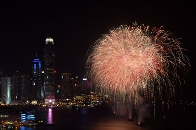 Firework display over illuminated buildings in city at night