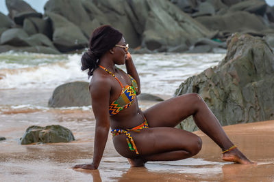 Africa ghana woman enjoying on a beach in traditional african colors on swimwear and navel percing