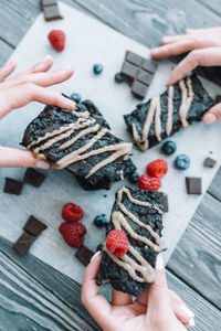 Cropped hands of woman holding gingerbread cookies on table