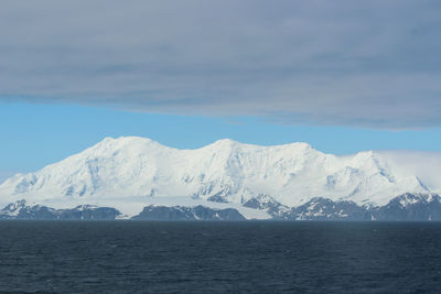 Scenic view of snowcapped mountains by sea against sky