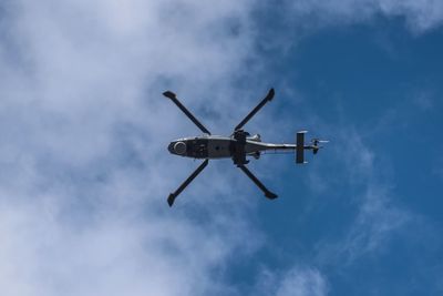 Directly below shot of helicopter flying in blue sky