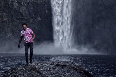Woman standing on rock against waterfall