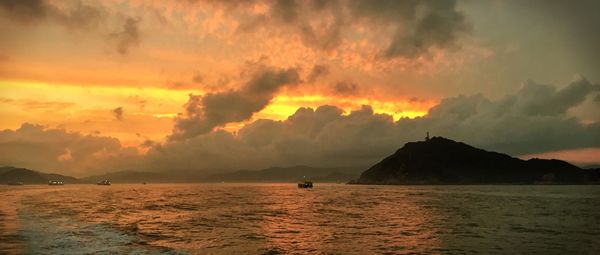 Scenic view of sea against cloudy sky at sunset