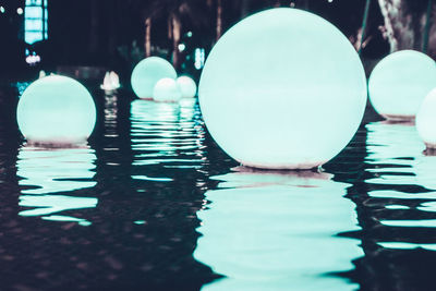 Close-up of illuminated ball in swimming pool with reflection on surface