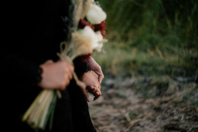 Close-up of woman holding hands on field