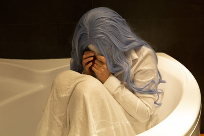 Woman with obscured face sitting in bathtub