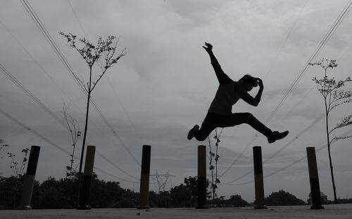 Low angle view of silhouette man jumping against sky