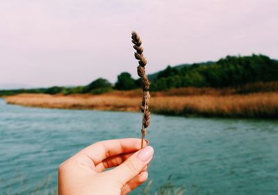 Close-up of hand holding water against lake