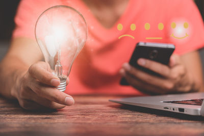 Midsection of man using mobile phone on table