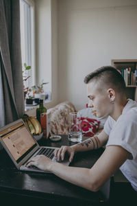 Side view of man sitting on table at home