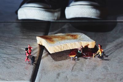 Artistic image of figurines cleaning bread and jam fallen on floor