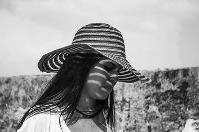 Close-up of woman looking down wearing hat against clear sky on sunny day