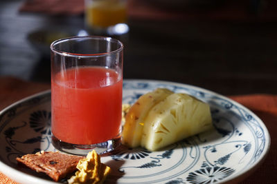 Plate of watermelon juice in a glass with fresh pineapple and dried fruits on the side