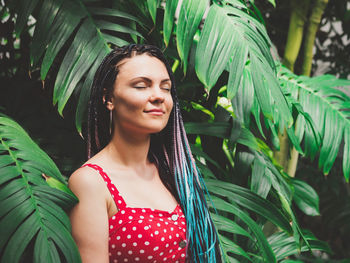 Woman with dreadlocks standing against plants