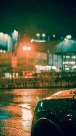 Close-up of wet car on illuminated street at night